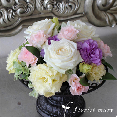 アンティーク調の花器に飾られたパステル系の花束（紫色白色のバラやカーネーション）