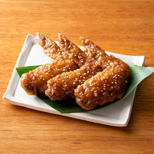 白色の皿に鶏手羽先の甘辛揚げが3本のっている。