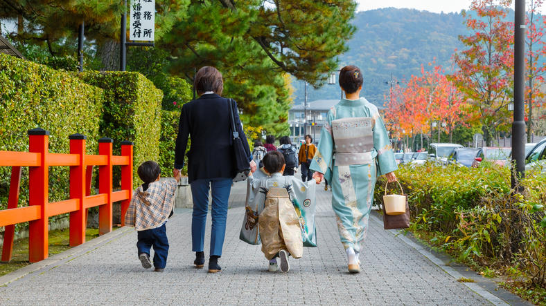 親子が手を引きながら歩いている後ろ姿