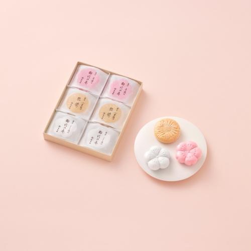 ピンク色の背景に、最中が3個のった白色のお皿と、最中が6個入った箱が置かれている。