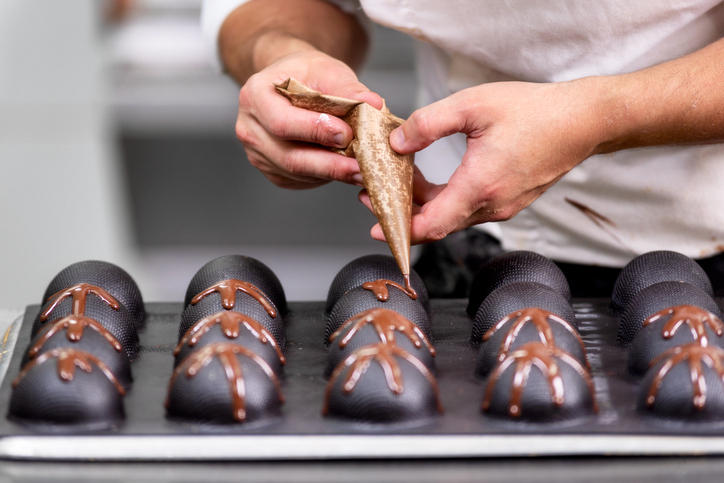 チョコレートケーキにデコレーションするパティシエの手元