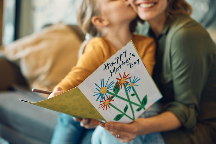 女の子がお母さんに「happy mother's day」とかかれたメッセージカードを贈っている