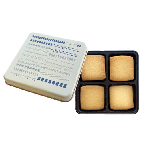 四角いバタークッキーが缶に詰め込まれており、その横には、白い缶の蓋が立てかけられている