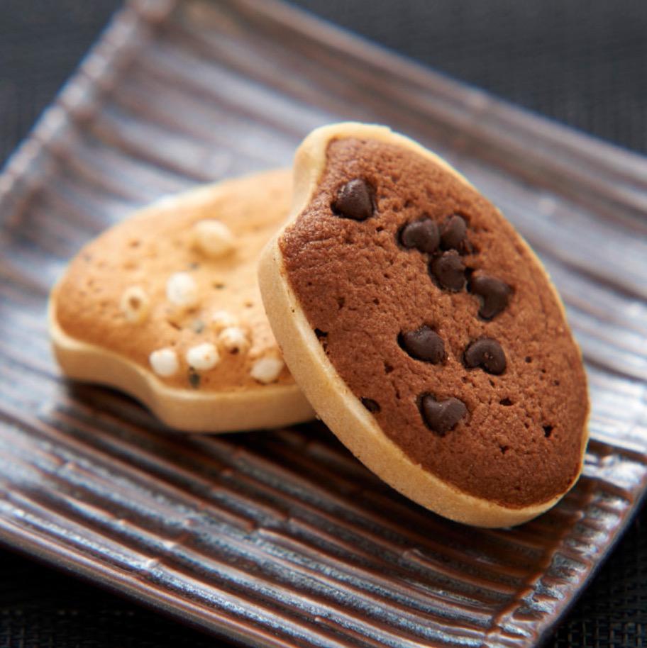 黒い背景に置かれた素焼きの四角い皿の上の2枚のクッキー
