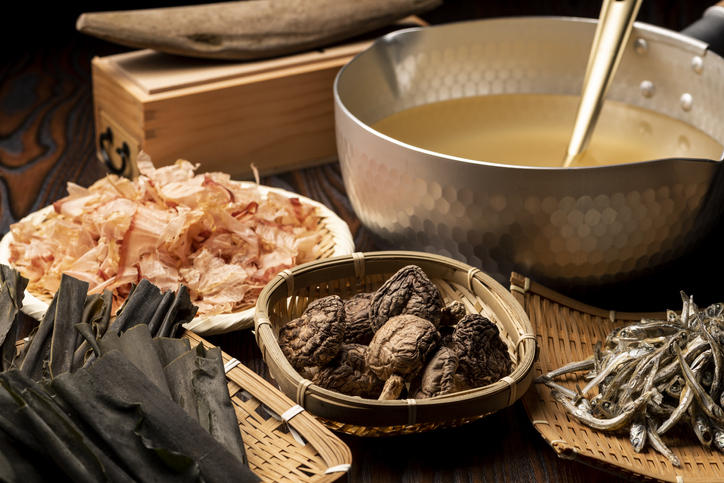 かつおぶし、昆布、しいたけ、煮干しが手前に置かれ、奥に出し汁が入った鍋が置かれている。