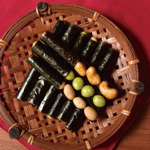 赤色のテーブルマットのうえに、豆を包んだ海苔菓子をのせたかご皿が置かれている