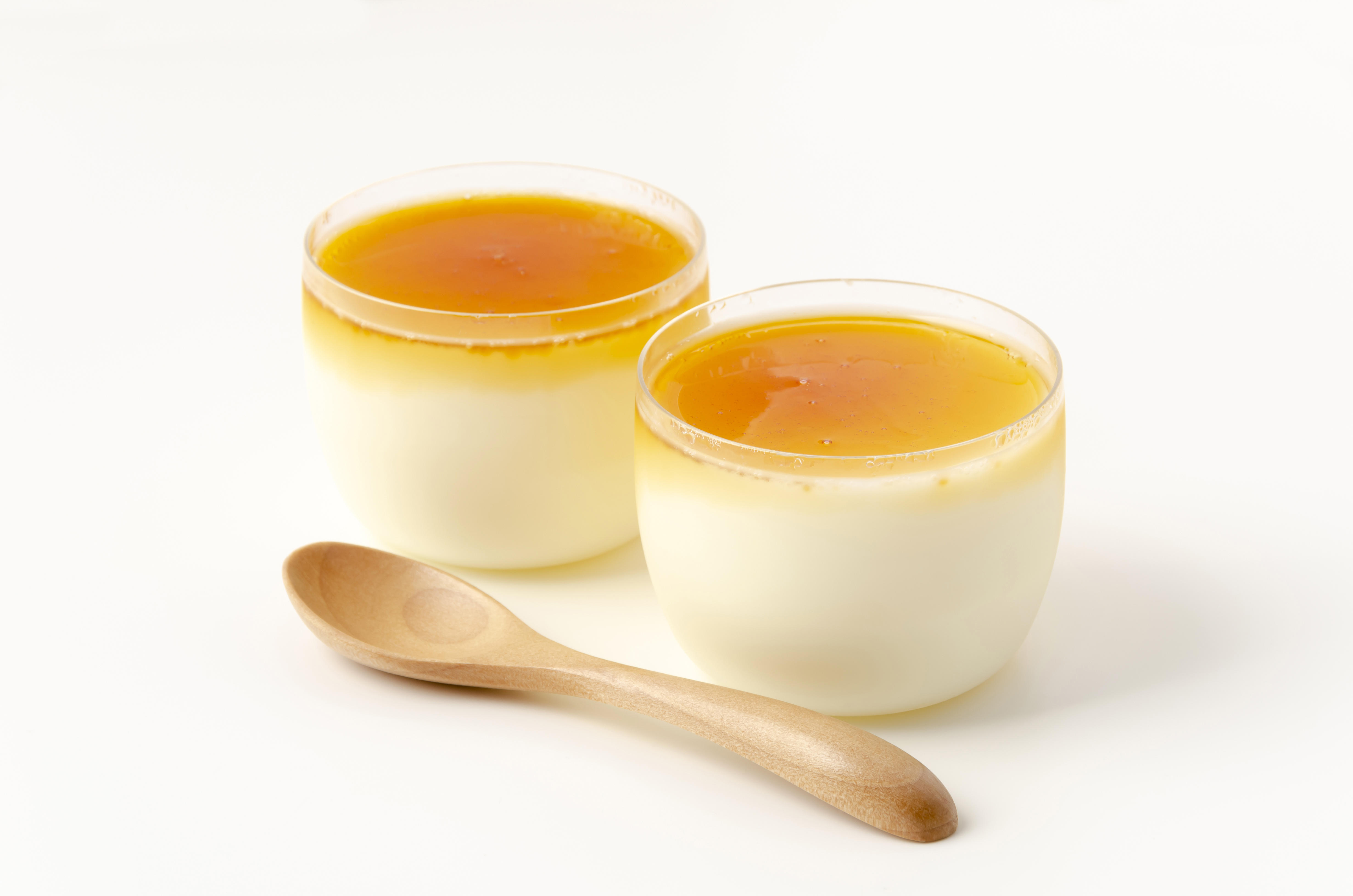 カップ入りのプリンが2つ並びスプーンが1本添えられている。