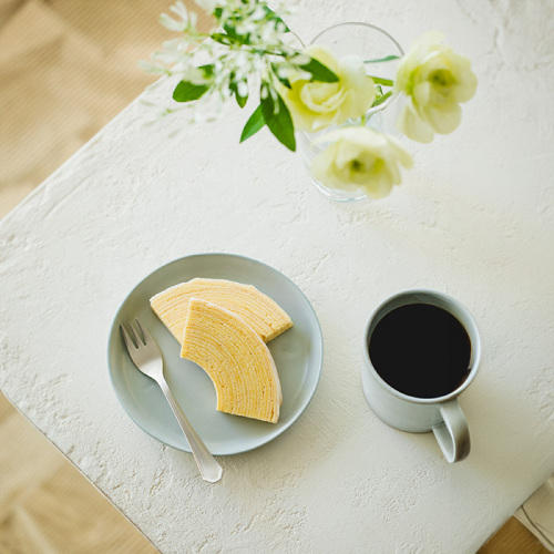 青い丸皿に盛られたユーハイムバウムとコーヒーとフォーク