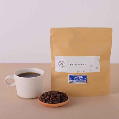 テーブルの上に、コーヒー入りカップ、コーヒー豆、茶色の袋が置かれている。