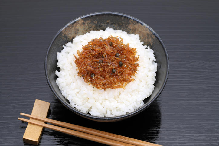 黒い背景に置かれた黒い茶碗のなかの白飯とちりめん山椒