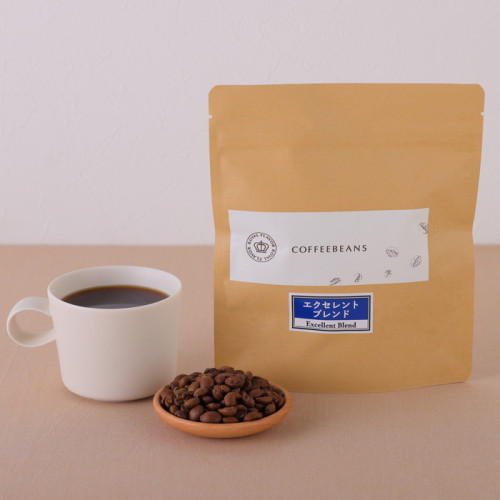 ロイヤルフレーバーのエクセレントブレンドのパッケージと皿に盛られた豆、白いカップに注がれたコーヒー