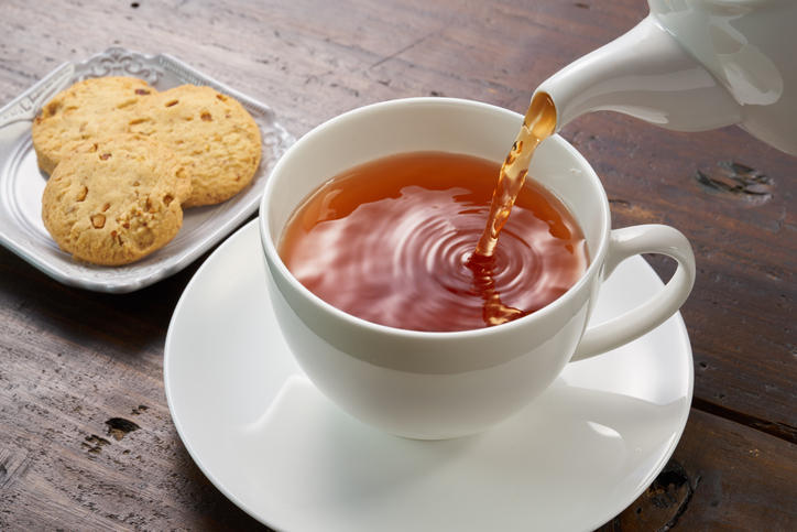 木製のテーブルの上で、ティーカップに紅茶を注いでいる。