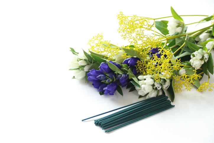白いテーブルに置かれた線香の束と紫・白・黄色の花