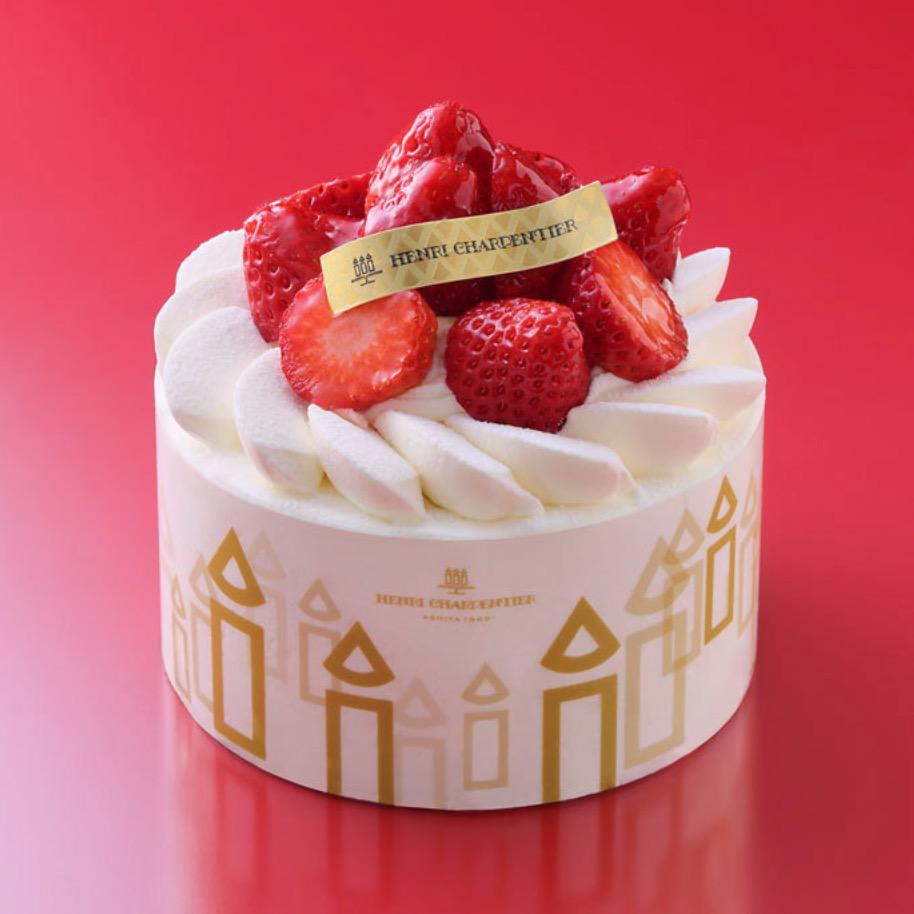 赤い背景に置かれたいちごたっぷりのショートケーキのホール