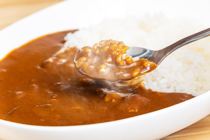白い皿に盛られたカレーを銀のスプーンですくう様子