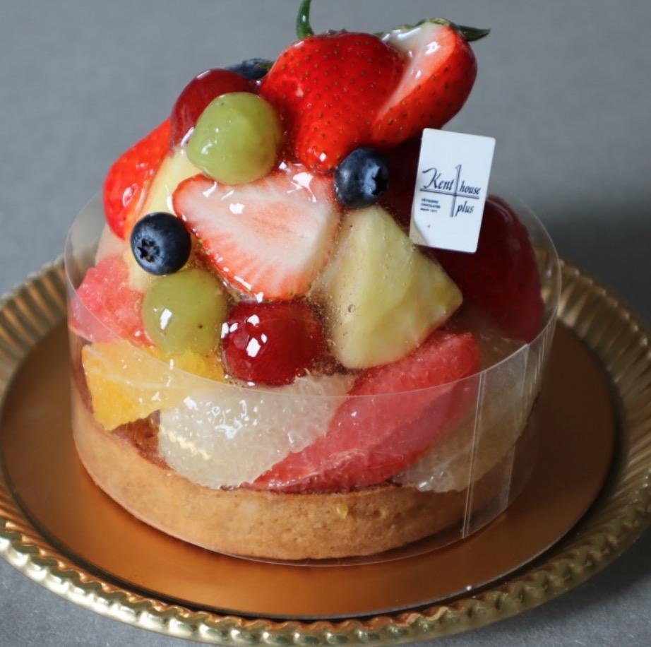 グレーの背景に置かれたゴールドの丸皿の上に置かれたフルーツケーキ