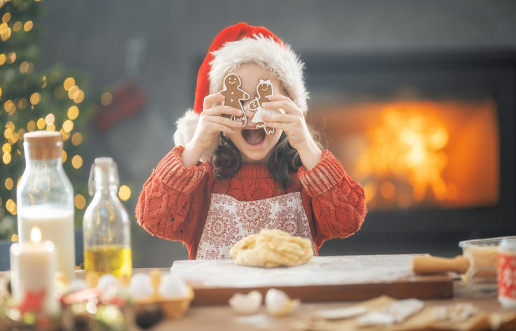 クリスマスの格好をした女の子がジンジャークッキーを作っている。