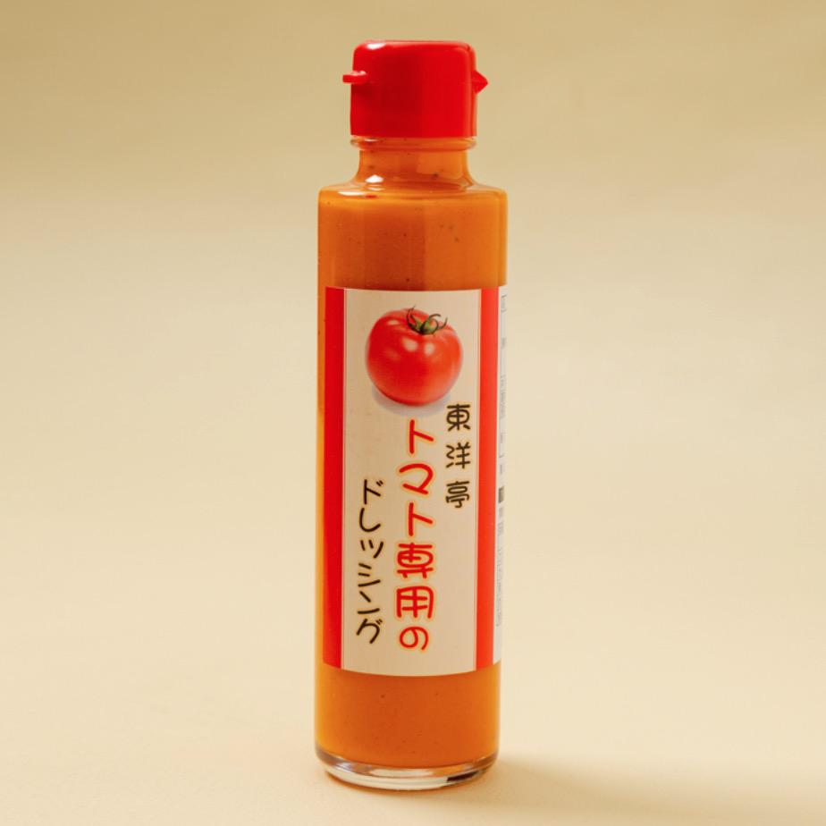 グレージュの背景に置かれたボトル入りの赤いドレッシング