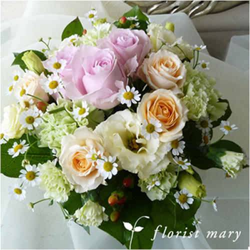 白い布の上のパステル系の花束（白や黄色、ピンク系のバラ、トルコキキョウ）