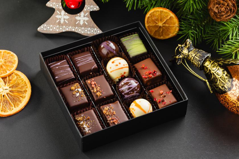 チョコが14個入った黒いボックスが置かれ、周りにはクリスマスの飾りが置かれている。