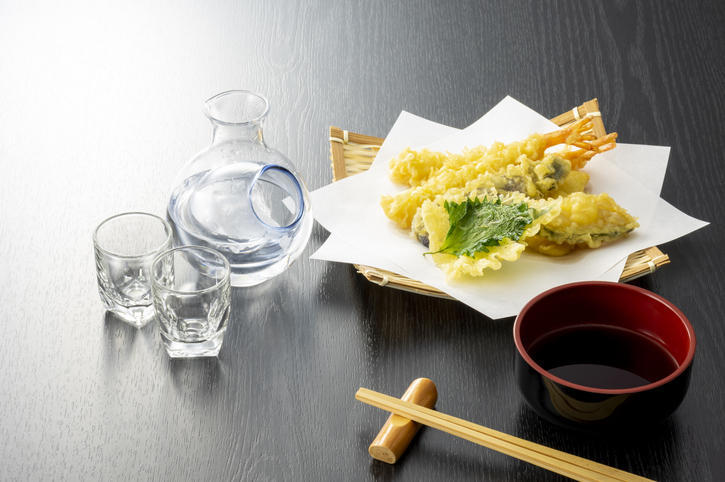 冷たい日本酒と天ぷらがテーブルに並べられている