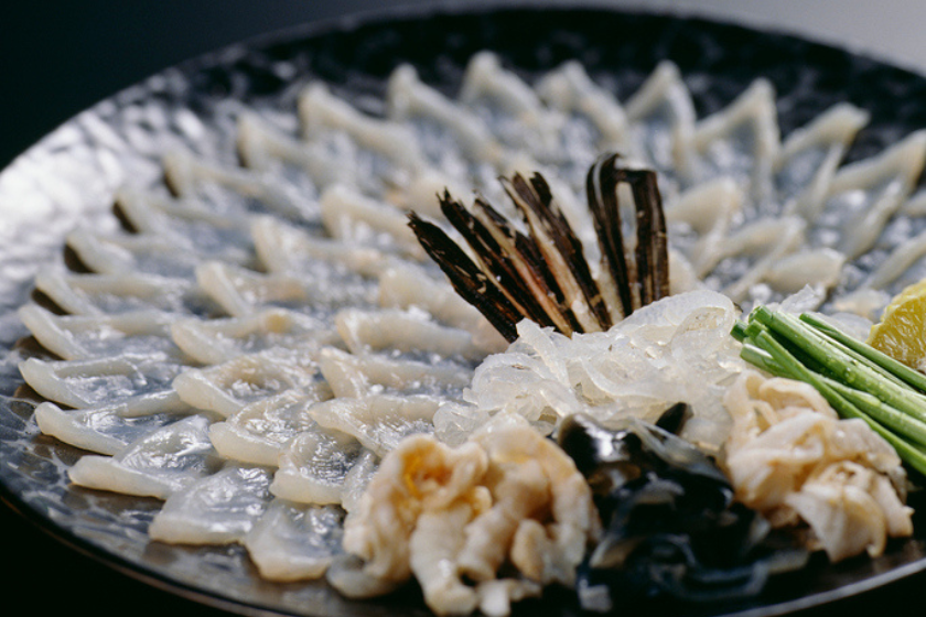 黒い和皿に美しく盛り付けられたふぐの刺身と薬味