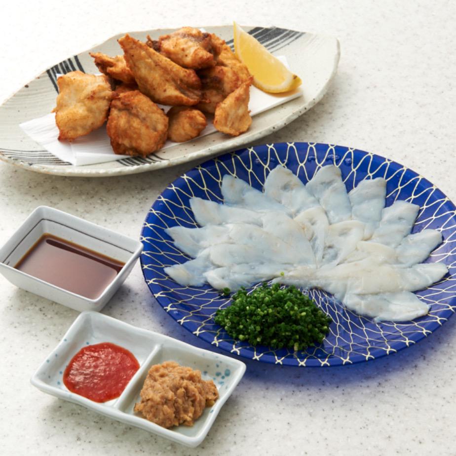 白い背景に置かれた青い丸皿の上のふぐの刺身と白い楕円形の皿の上のふぐの唐揚げ