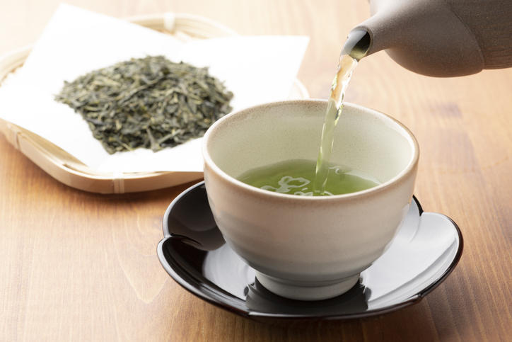 緑茶の茶葉と、緑茶が注がれた湯呑みが置かれている。