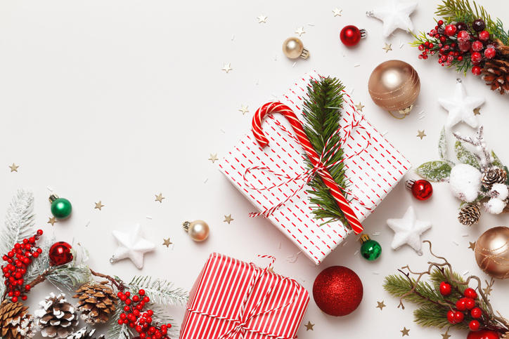 白色の背景に、クリスマスプレゼント、もみの木の枝、オーナメントなどが置かれている。