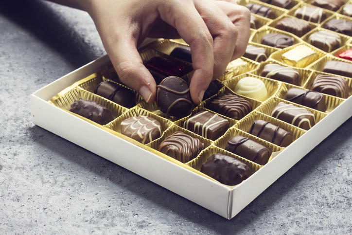いくつものチョコレートが入った箱の中に手を伸ばす様子