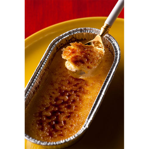 黄色い丸皿の上に、楕円形のアルミカップに入った焼きプリン・フローズンデザートが置かれ、スプーンですくわれている