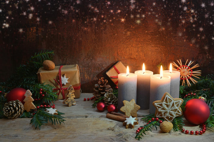 プレゼントやツリーなどのクリスマスオーナメントと、火のついた4つの太いろうそく