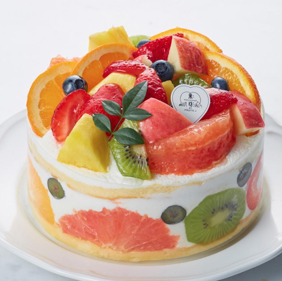 白い丸皿に乗ったたくさんのフルーツを使ったホールケーキ