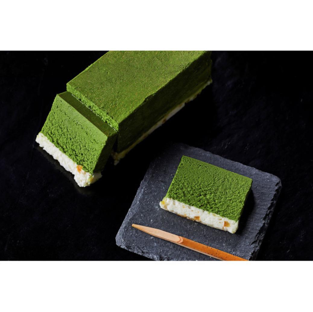 黒い背景に置かれた抹茶のテリーヌ1本と黒い正方形の皿に置かれたスライスの抹茶テリーヌと竹楊枝
