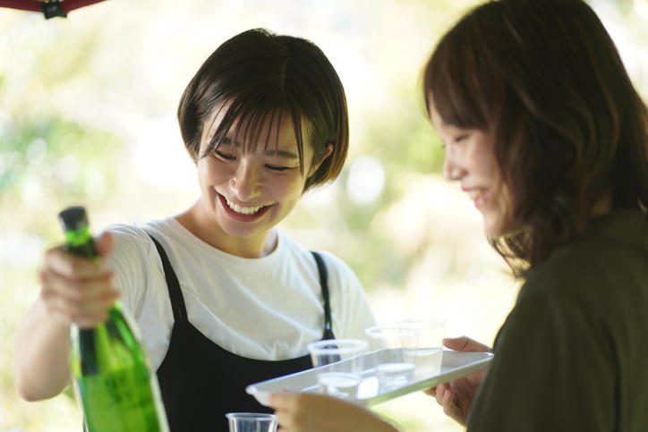 女性2人が日本酒の瓶を持って試飲している