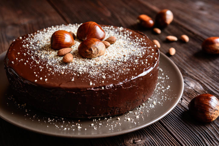 ブラウンの背景に置かれた丸皿の上のチョコレートのホールケーキ