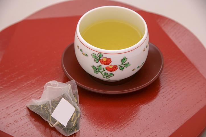 朱塗りのトレイに置かれた湯呑とお茶のティーバッグ