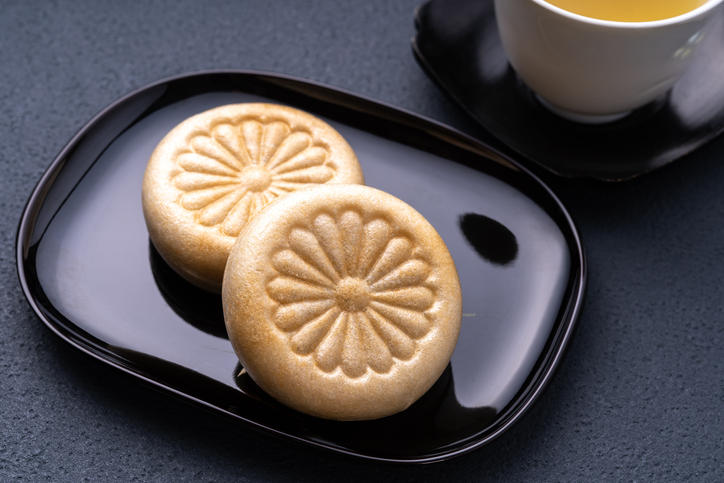 黒い皿にのせられた菊の模様入りのふたつの最中