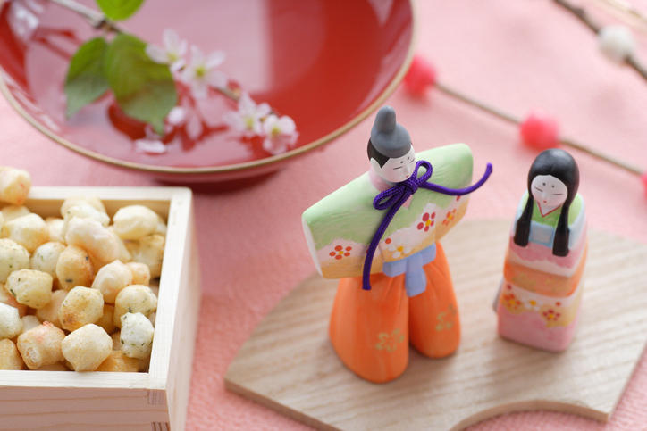 桃色の背景に縁起の良い豆やマスコットの雛人形が並べられている