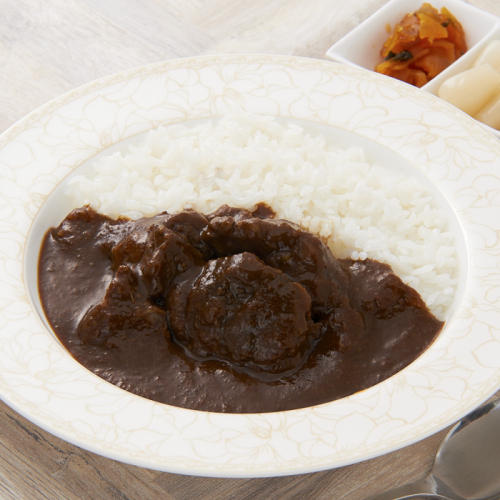 牛肉の塊が入ったカレーライスと福神漬けが置かれている。