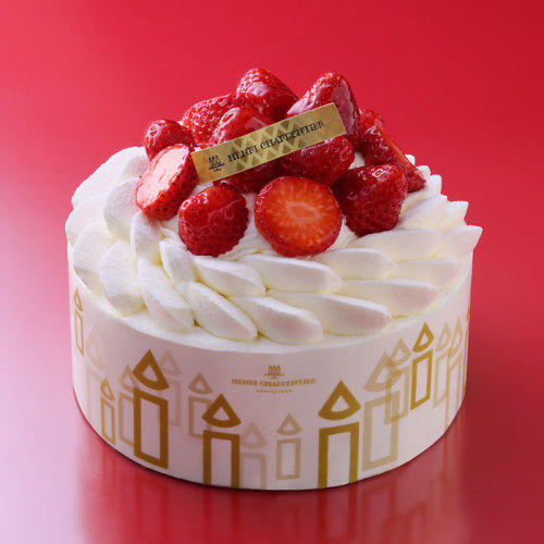 赤色の背景に、ホールのいちごのショートケーキが置かれている。