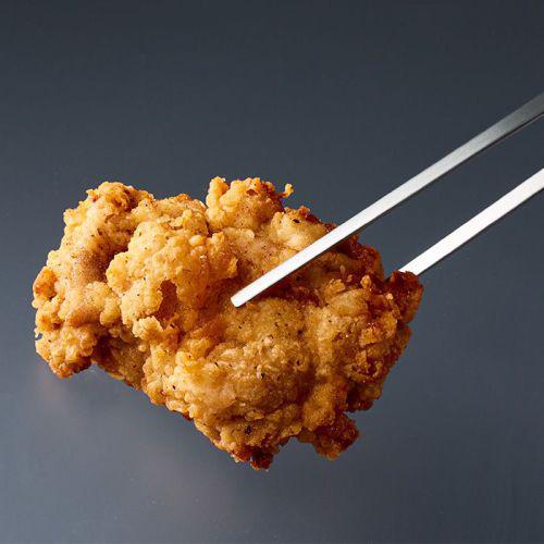 箸でつかまれたジーズメニューの骨なしフライドチキン