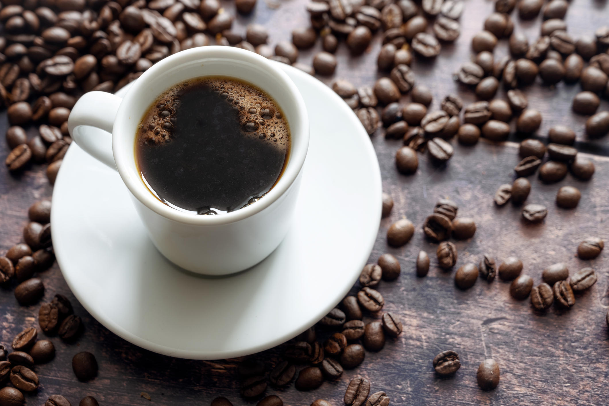 テーブルに置いたコーヒーカップと、散らばったコーヒー豆