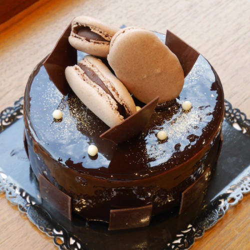 マカロンとグラサージュでデコレーションされたホールのチョコレートケーキ