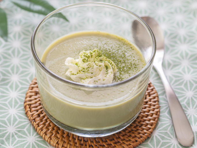 抹茶プリンが入った透明の器がコースターの上に置かれている。