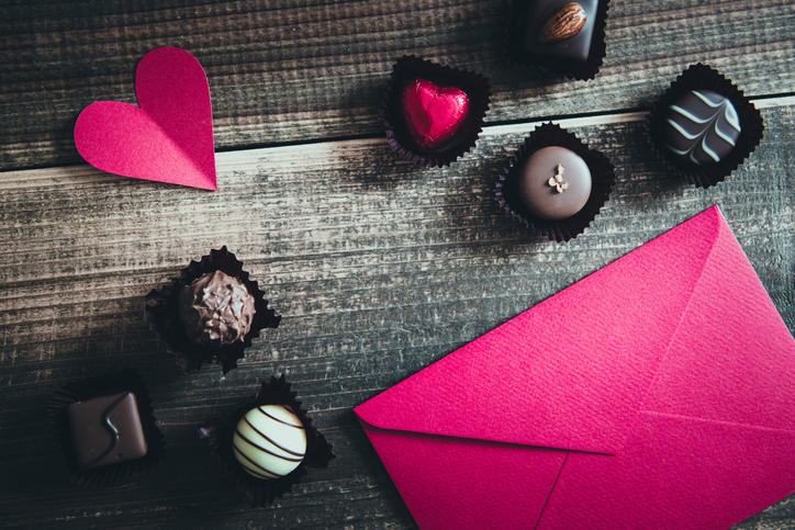 木製のテーブルに置かれたチョコレートとピンク色の封筒