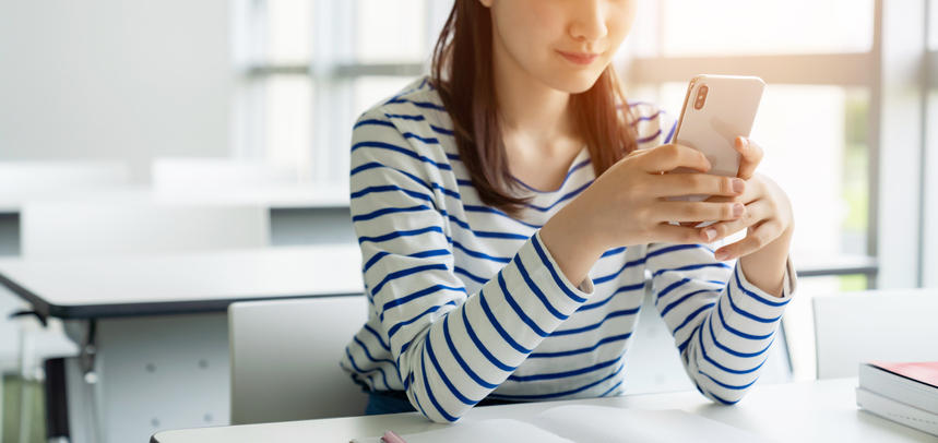 テーブルでスマートフォンを手に持つ女性