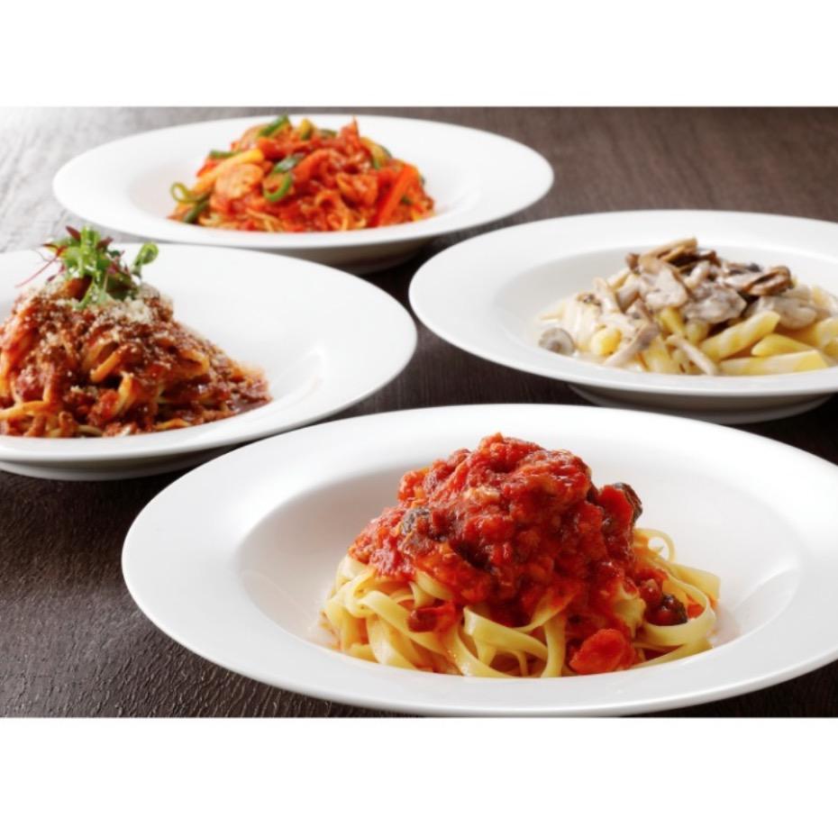 木製のテーブルに並んだ白い丸皿に盛られた4種類のパスタ