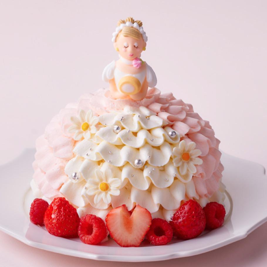 ピンクの背景に置かれた皿の上のプリンセスを模ったケーキとベリー