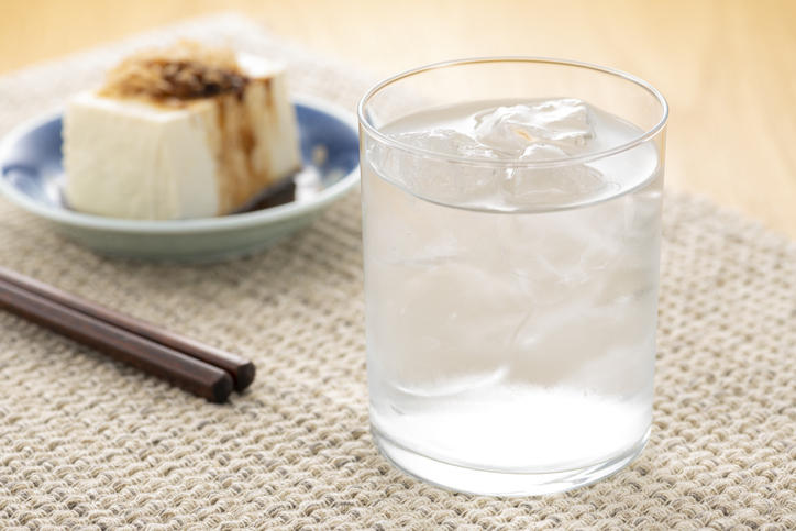 グラスに入った水割りの焼酎と奥に冷奴